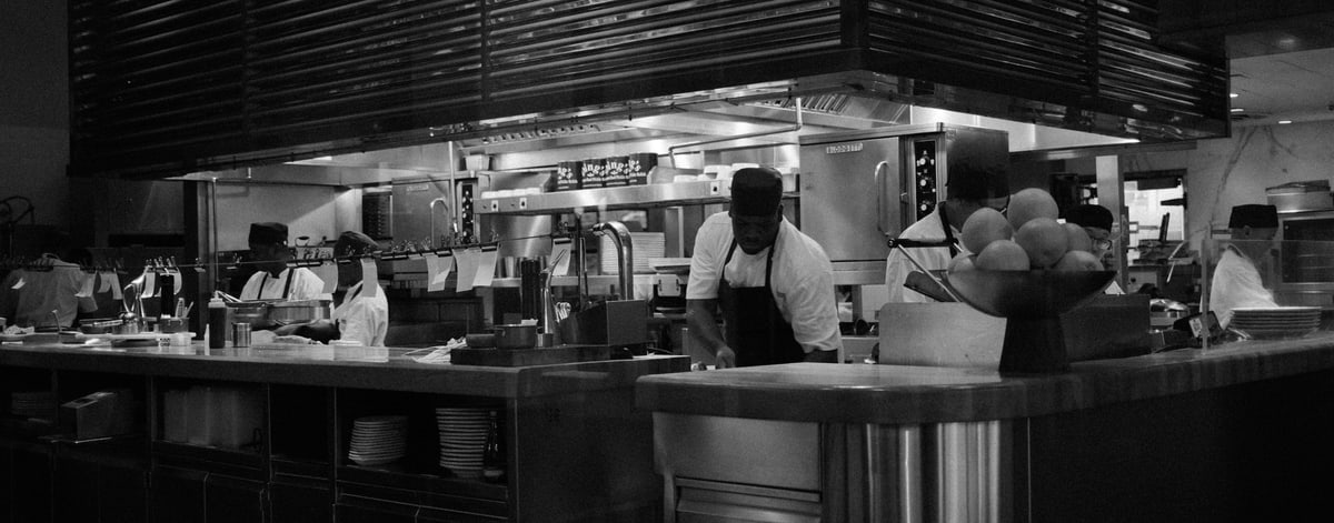 Chefs working the line in an open restaurant kitchen during service